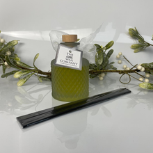 Green candle with wooden wick and decorative mistletoe on a white background