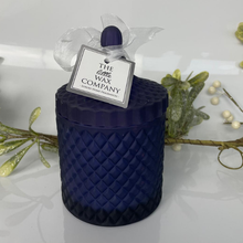 Blue textured candle with a decorative tag on a white background