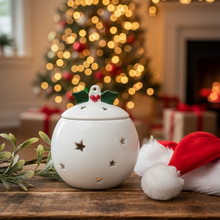 Decorative white lantern with a bird design on top, surrounded by Christmas decorations including a tree and presents.
