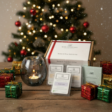 Wax Company gift set with candles and small boxes in front of a decorated Christmas tree.