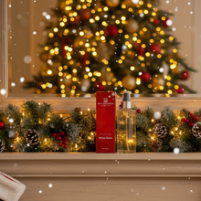 Decorative shelf with a Christmas tree in the background, featuring a red box and a bottle.