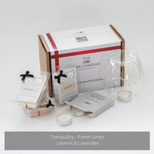 A gift set from The Little Wax Company including a grey/blue glass tea light burner and three packs of wax melts, with the fragrances Tranquility, Fresh Linen, and Lemon & Lavender visible.