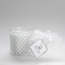 A clear cut glass candle with a geometric lid and a white ribbon, labeled with 'The Little Wax Co.'