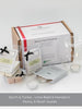 A gift set including a grey/blue glass tea light burner and three packs of luxury wax melts in different fragrance names displayed alongside a box with branding visible.