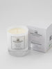 A small white candle with a label that reads 'Myrrh & Tonka' alongside a white box with the same label and brand, The Wax Company.